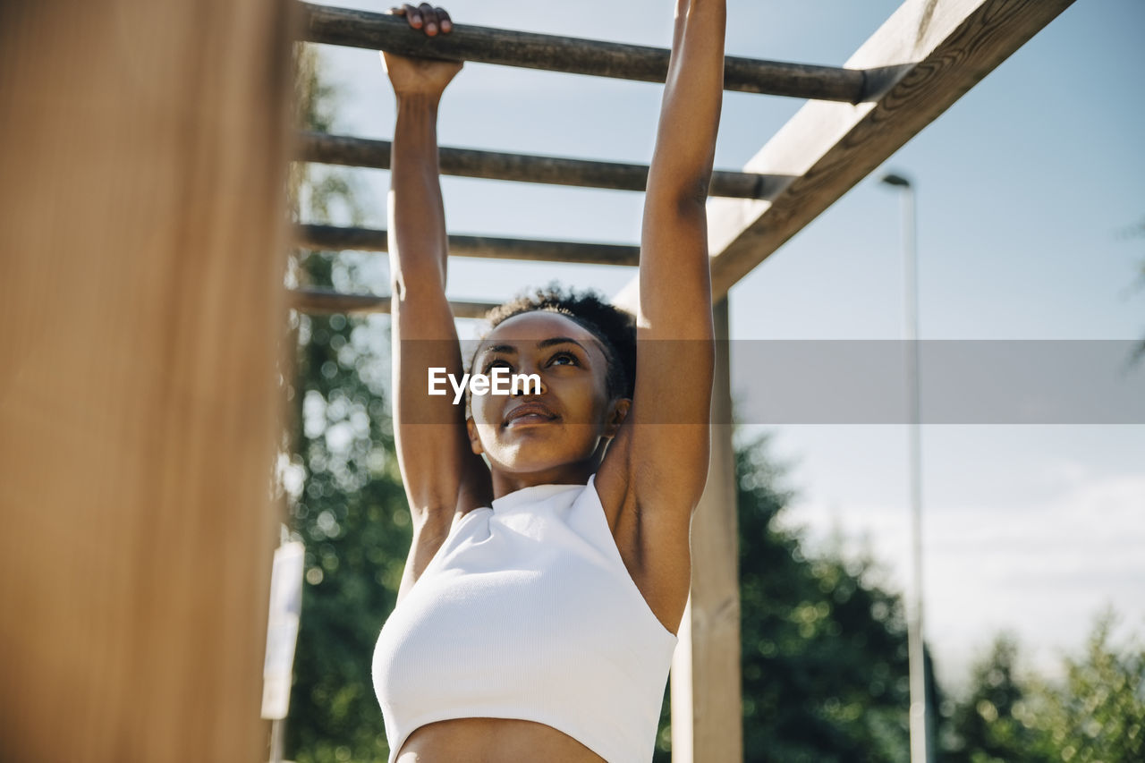 Female athlete hanging on monkey bar in park