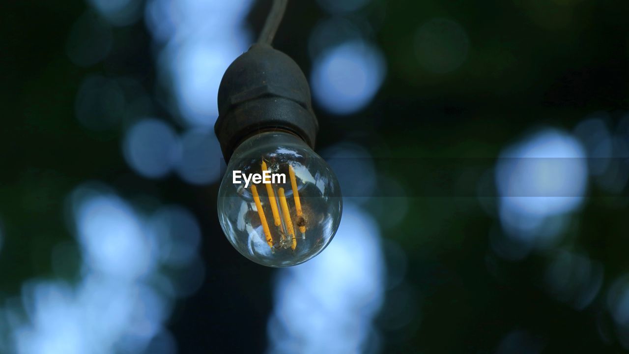 CLOSE-UP OF LIGHT BULB HANGING ON GLASS