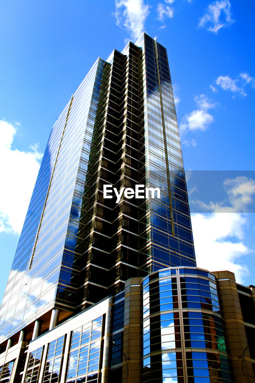 Low angle view of modern building with reflection of sky