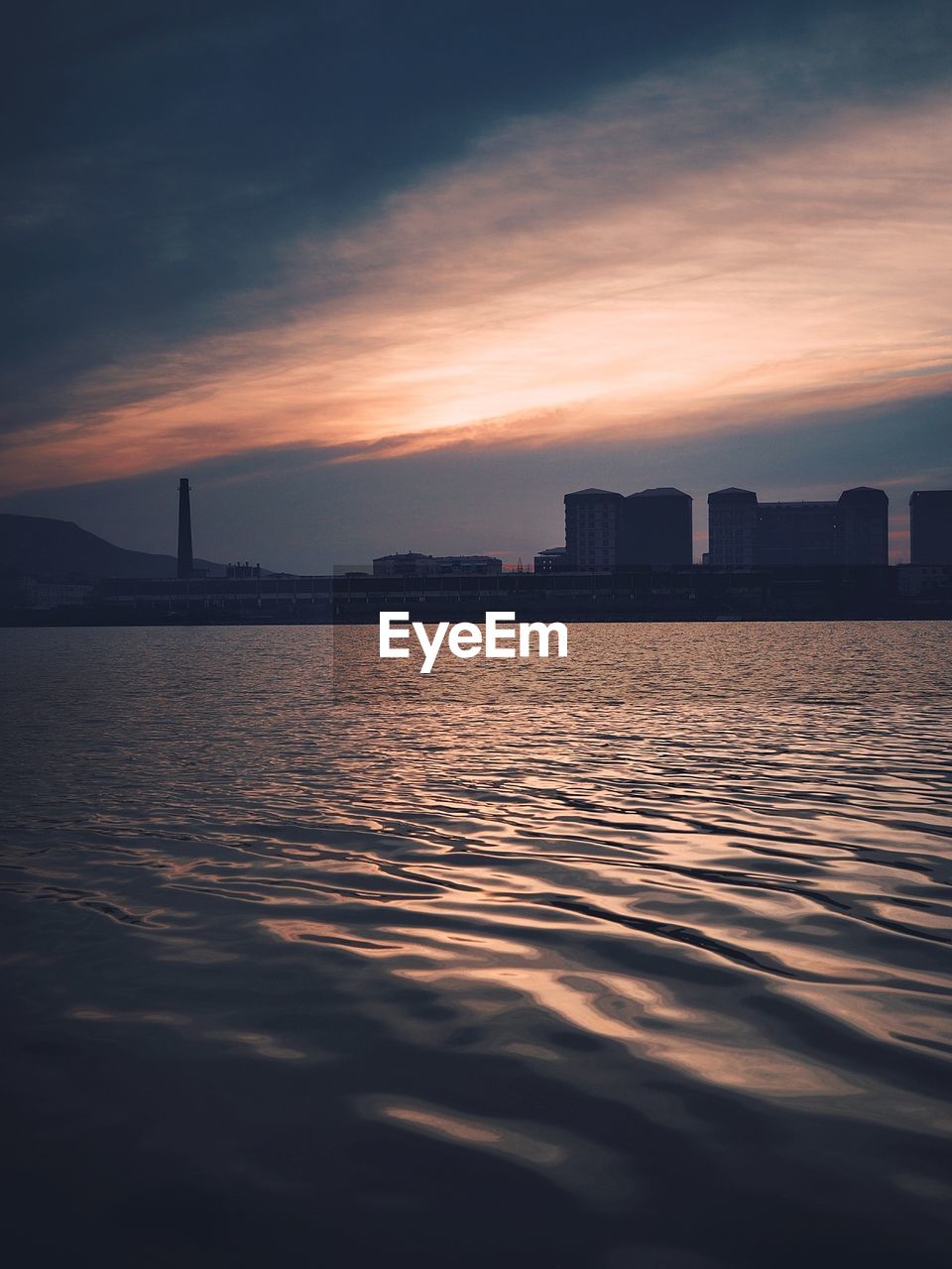 SILHOUETTE BUILDINGS AND SEA AGAINST SKY DURING SUNSET