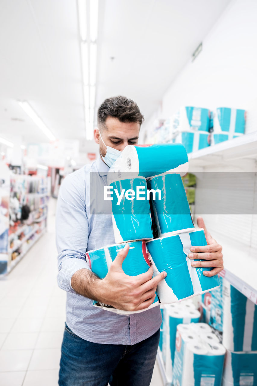 Mountain of toilet paper packages held by a man before purchase in a supermarket.t. stock piling 