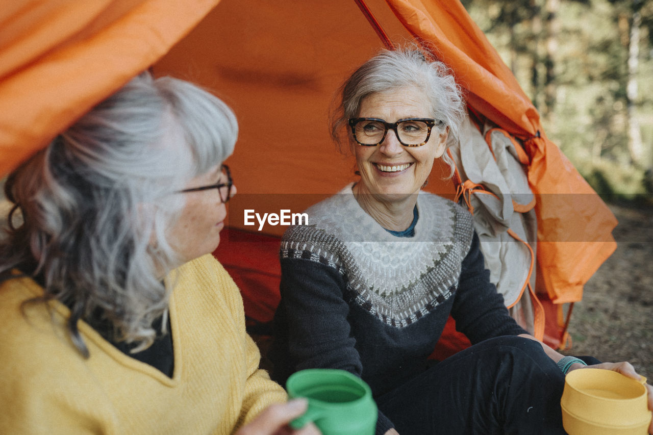 Two senior women sitting in front of tent at campsite