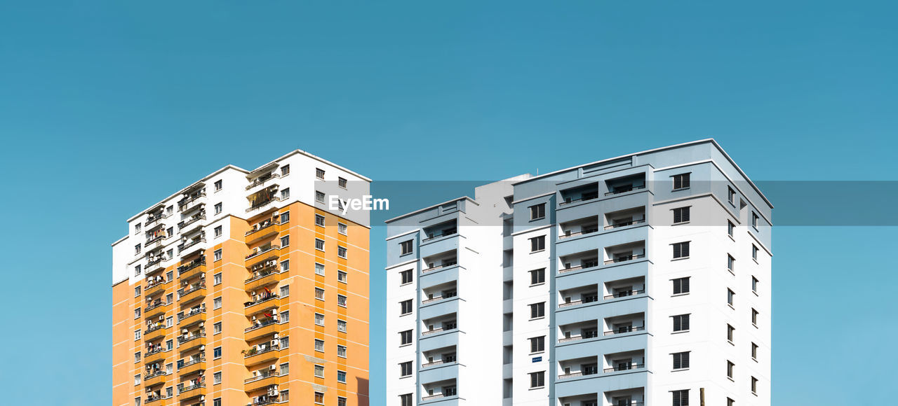 Low angle view of apartment building against clear blue sky