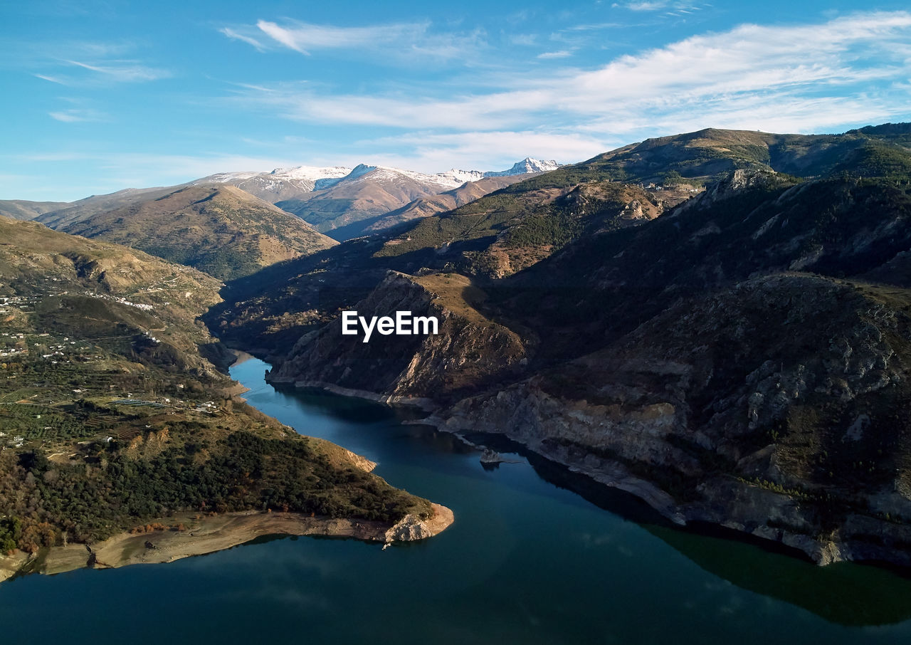 Aerial view of lake by mountains against sky