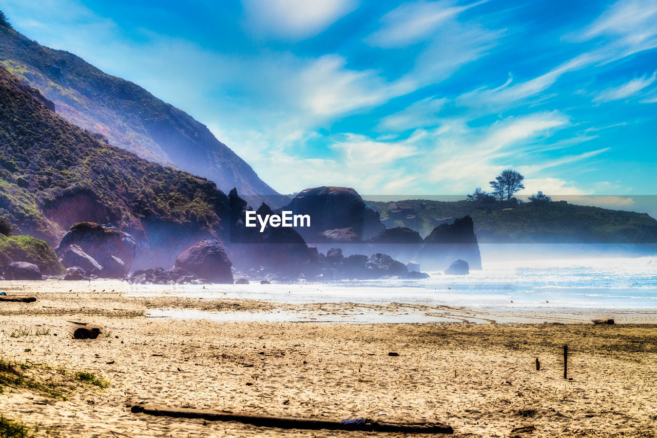 environment, land, landscape, sky, scenics - nature, mountain, water, nature, beauty in nature, sea, cloud, wave, coast, travel destinations, travel, horizon, morning, beach, ocean, fog, shore, blue, tranquility, outdoors, tourism, body of water, no people, sunlight, sun, mountain range, tranquil scene, sand, rock, sunrise, wind wave, cold temperature, dramatic sky, motion, summer, holiday, non-urban scene