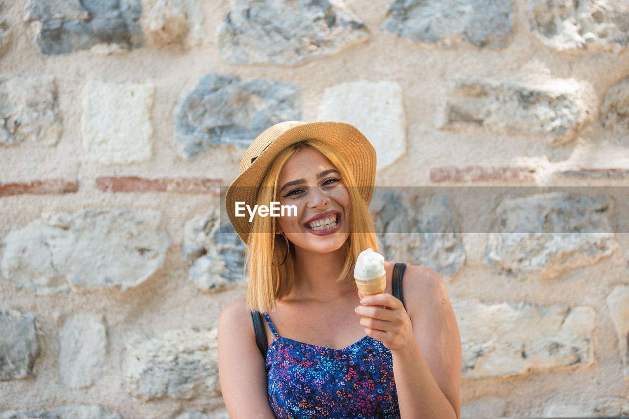 Portrait of a beautiful young woman drinking against wall