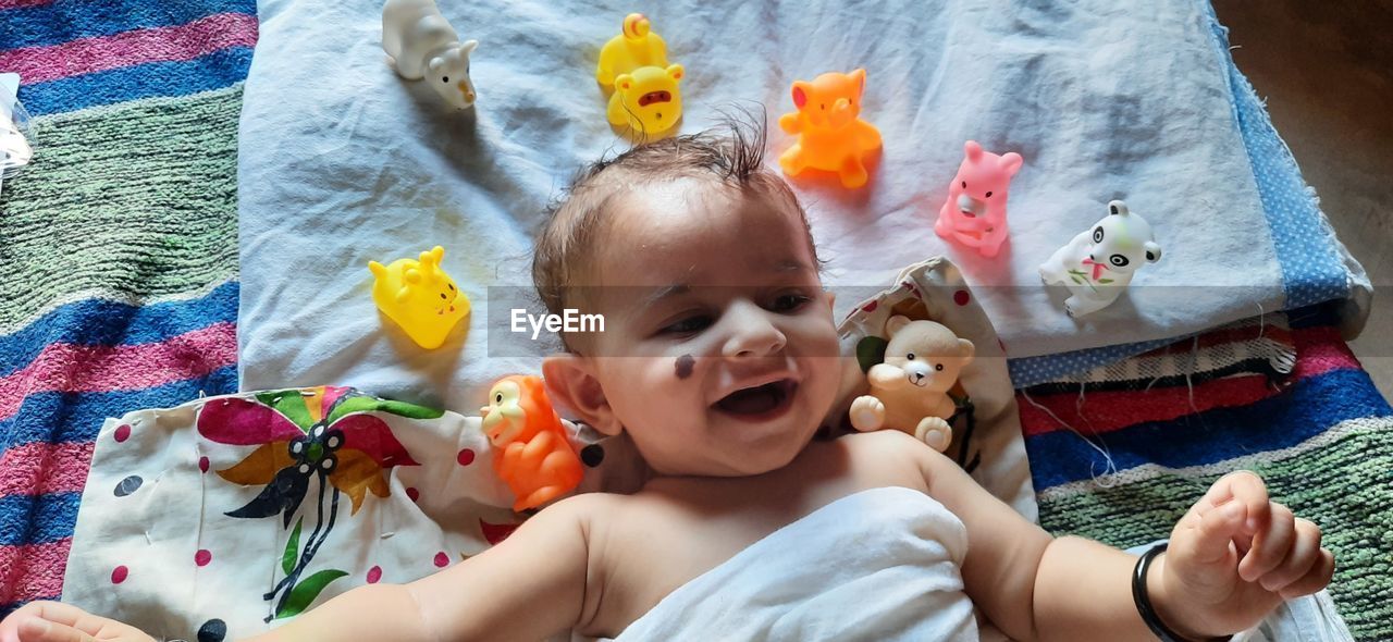 HIGH ANGLE VIEW OF CUTE BABY LYING DOWN ON SOFA