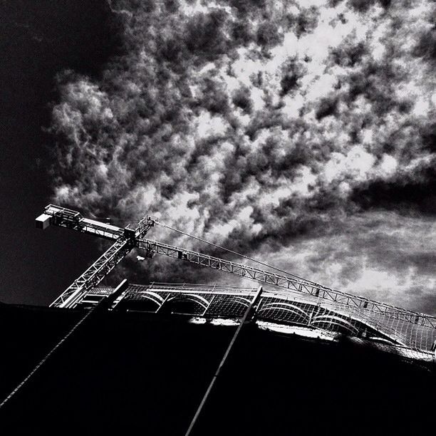 LOW ANGLE VIEW OF CRANES AGAINST CLOUDY SKY