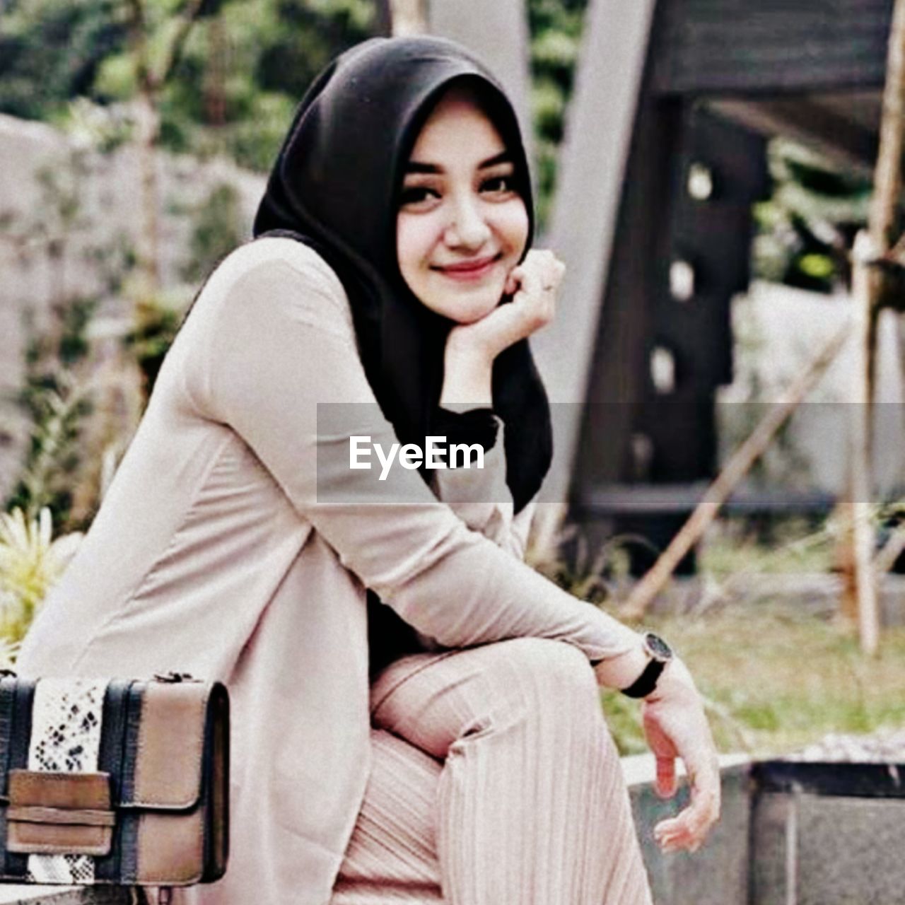 PORTRAIT OF SMILING WOMAN SITTING OUTDOORS