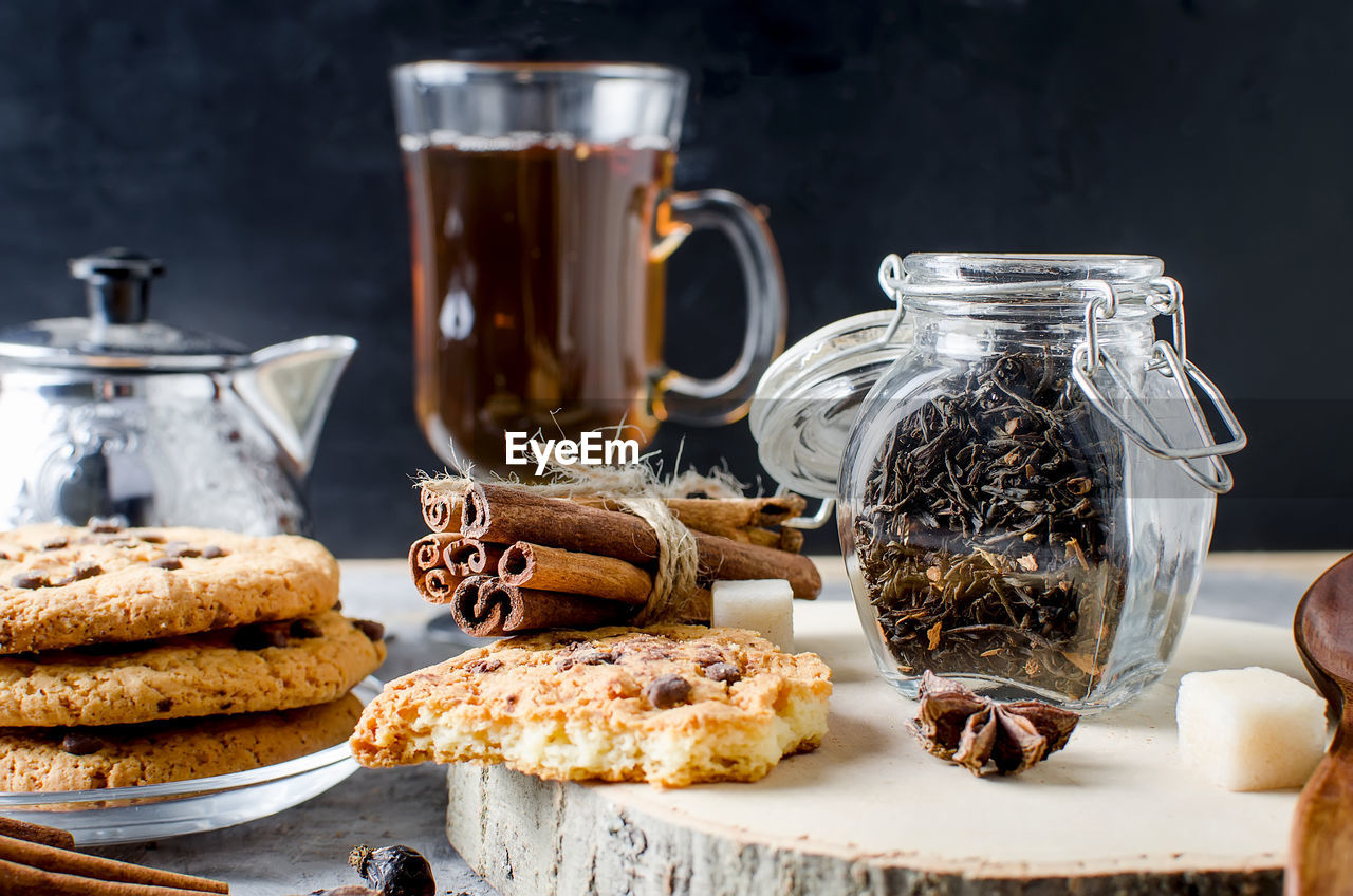 Close-up of ingredients by cookies and cinnamons in jar on cutting board