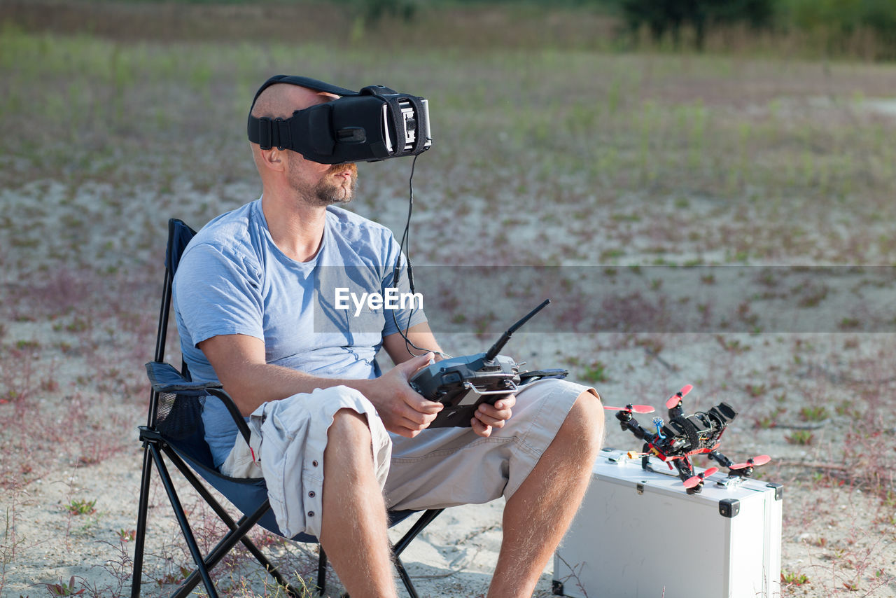 Man using virtual headset while sitting outdoors