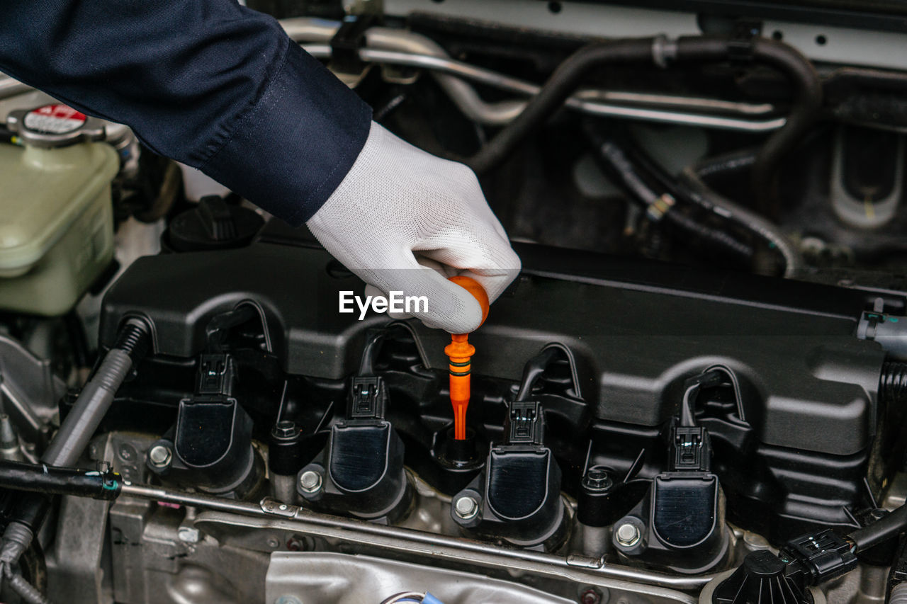 Mechanic man checking car engine oil of the car in the garage.