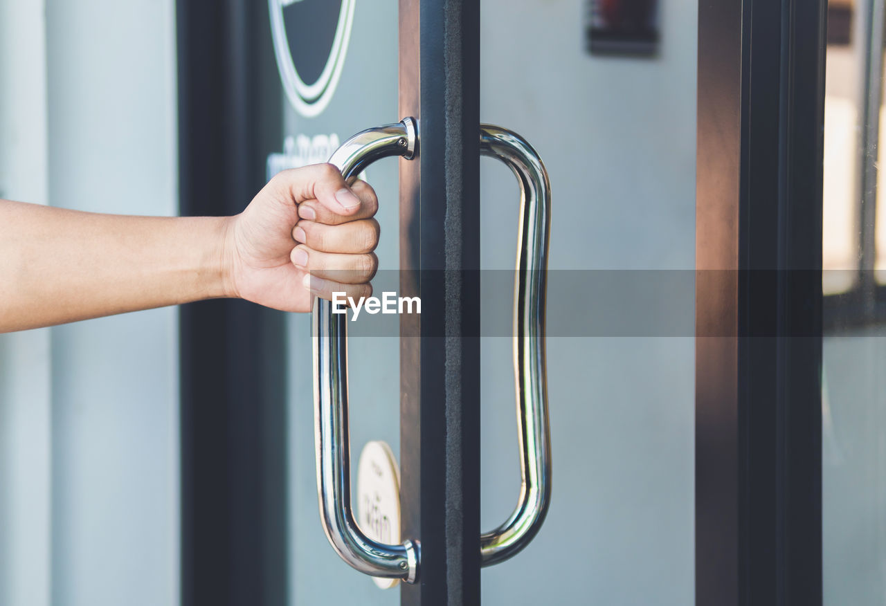 Close-up of hand holding handle of door