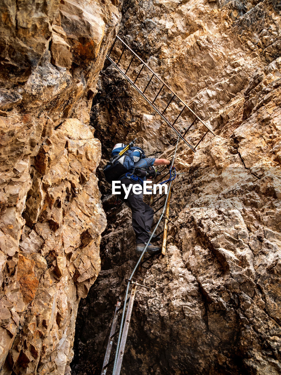 Low angle view of senior man climbing on rocky mountain