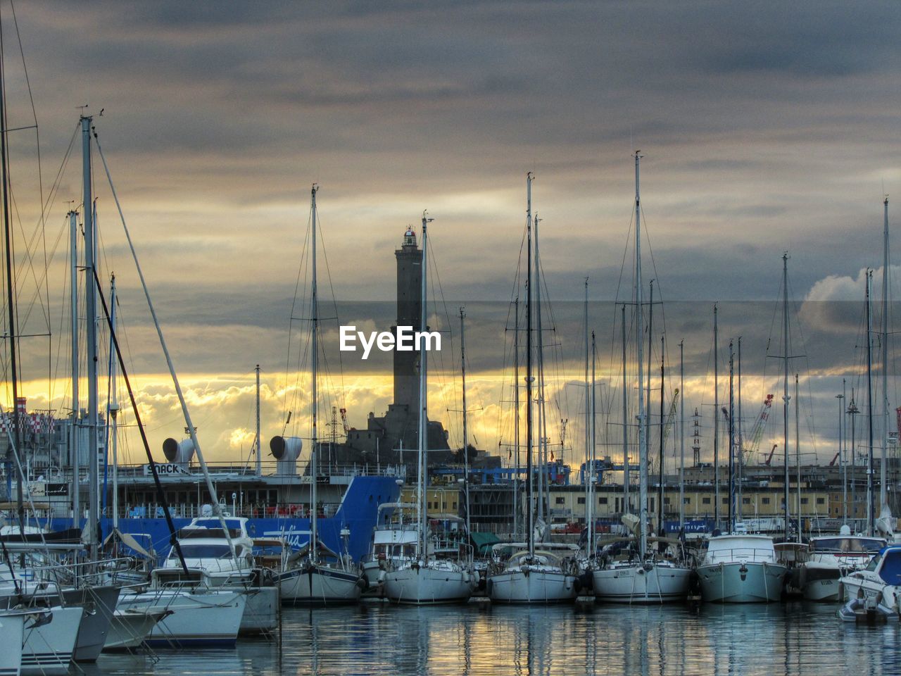 Boats moored at harbor against cloudy sky