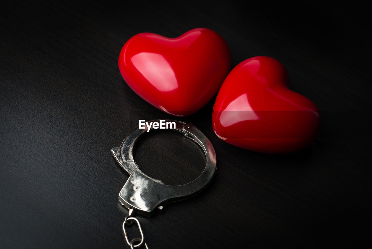 Close-up of heart shapes and handcuffs on black background