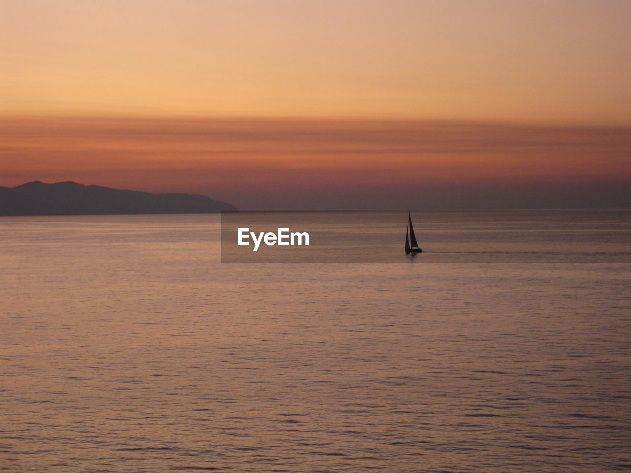 Sailboat sailing on sea against sky during sunset