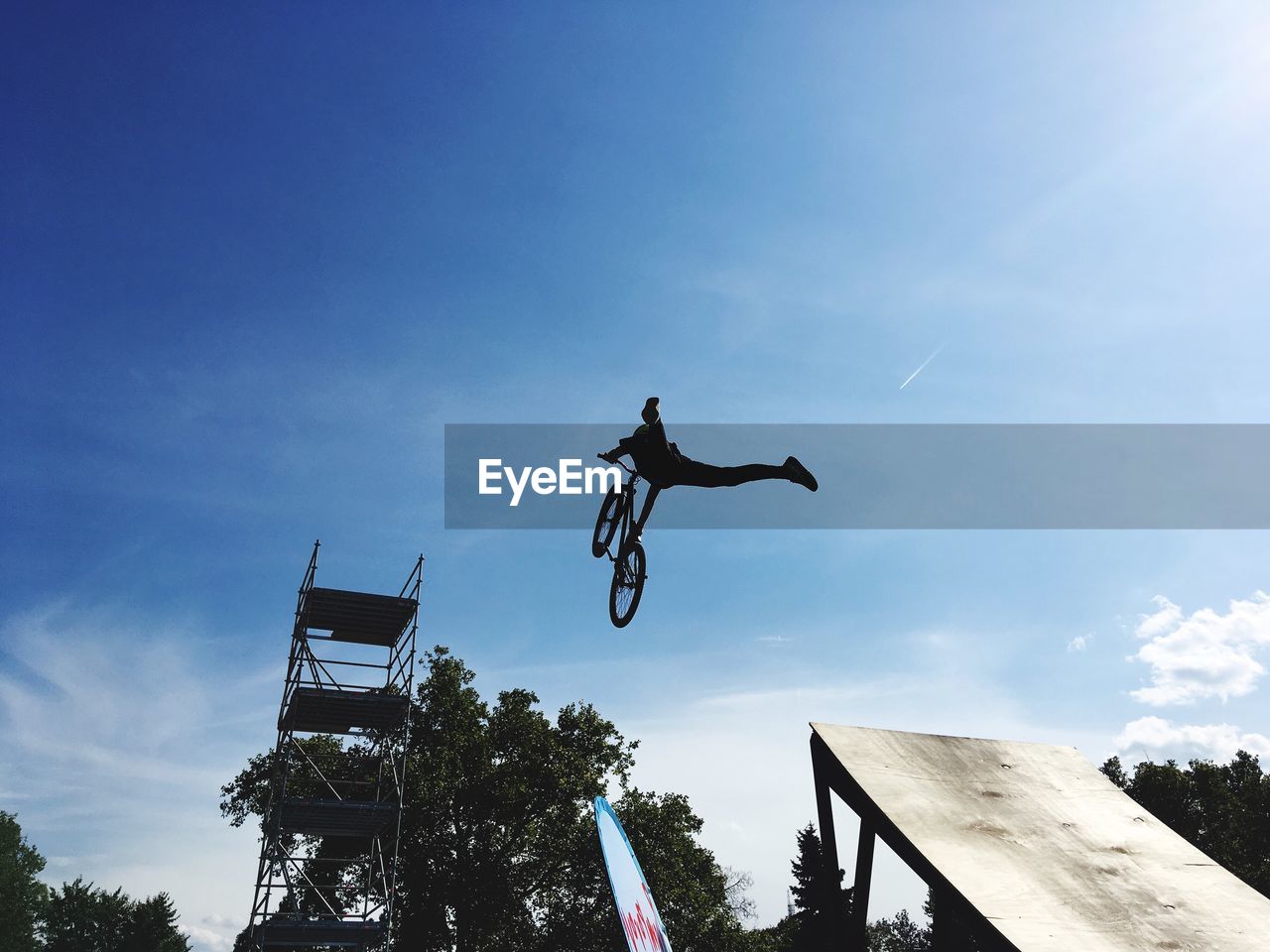 LOW ANGLE VIEW OF MAN JUMPING ON CABLE