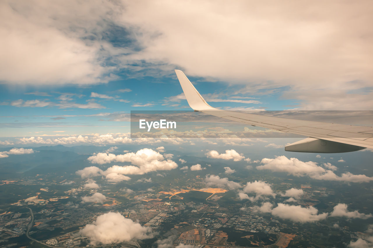 Airplane wing seen through window against sky