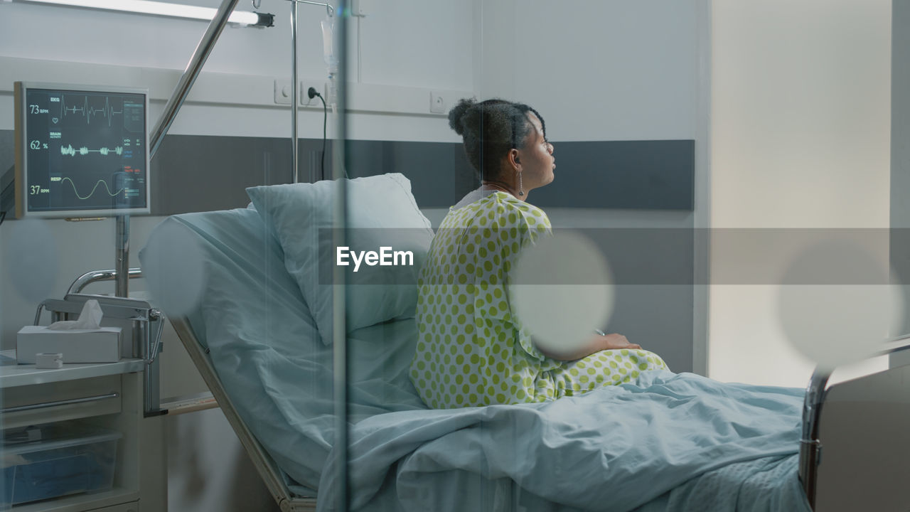 Young woman sitting on bed in hospital