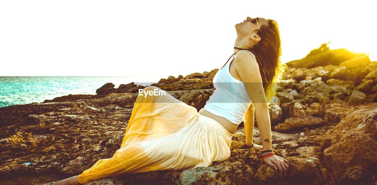 Side view of woman sitting on rock