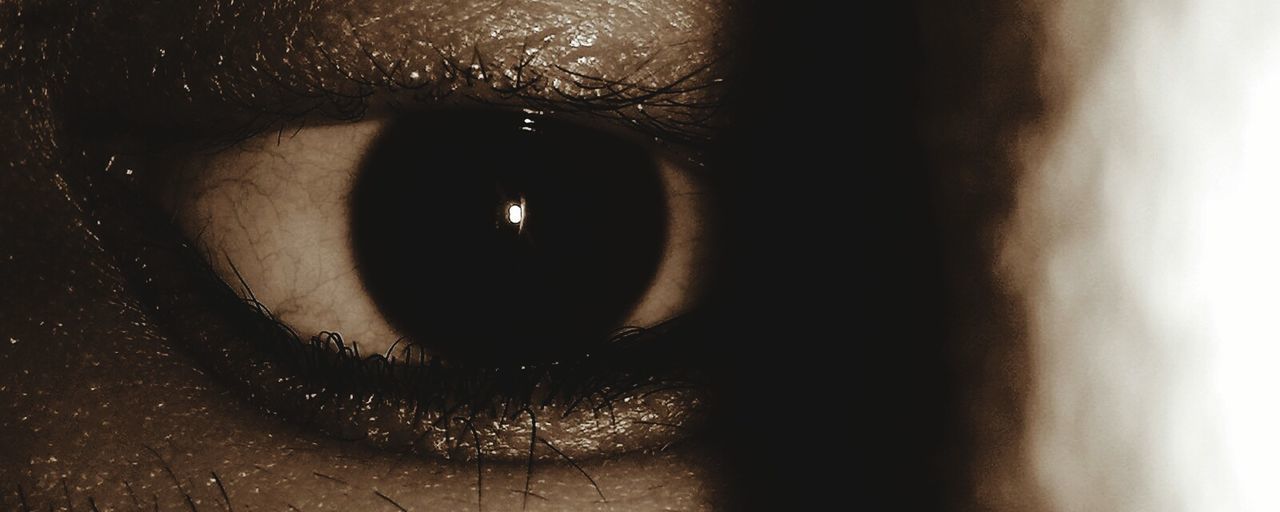 CLOSE-UP OF HUMAN EYE IN DARK ROOM