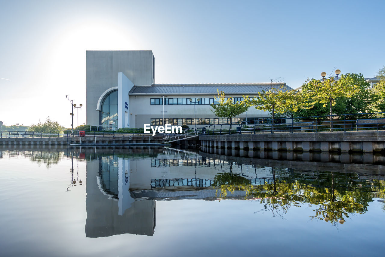 REFLECTION OF BUILDING IN LAKE AGAINST SKY