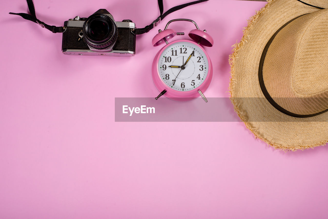 CLOSE-UP OF CLOCK ON TABLE AGAINST COLORED BACKGROUND