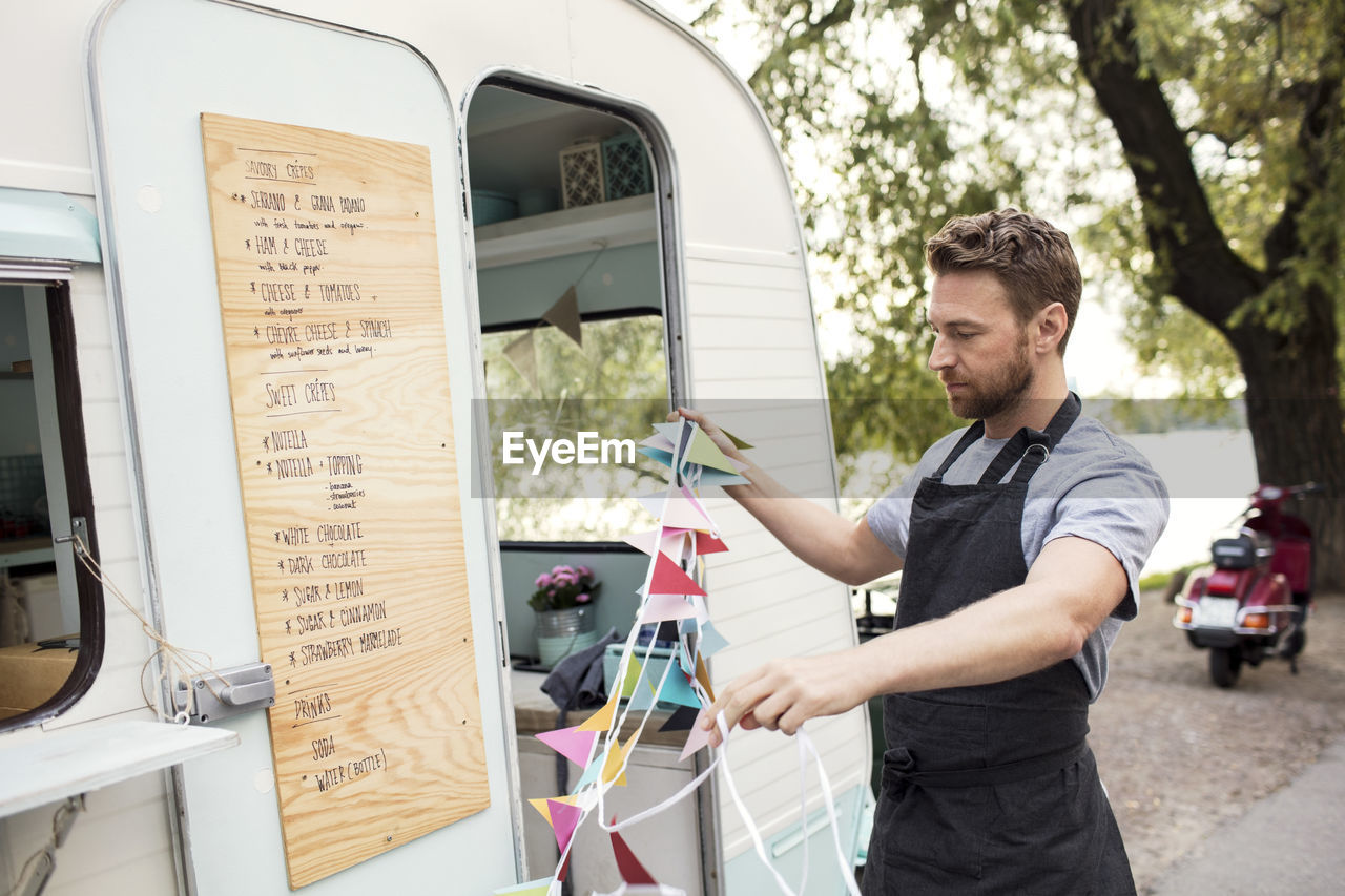 Male owner holding bunting flags outside food truck