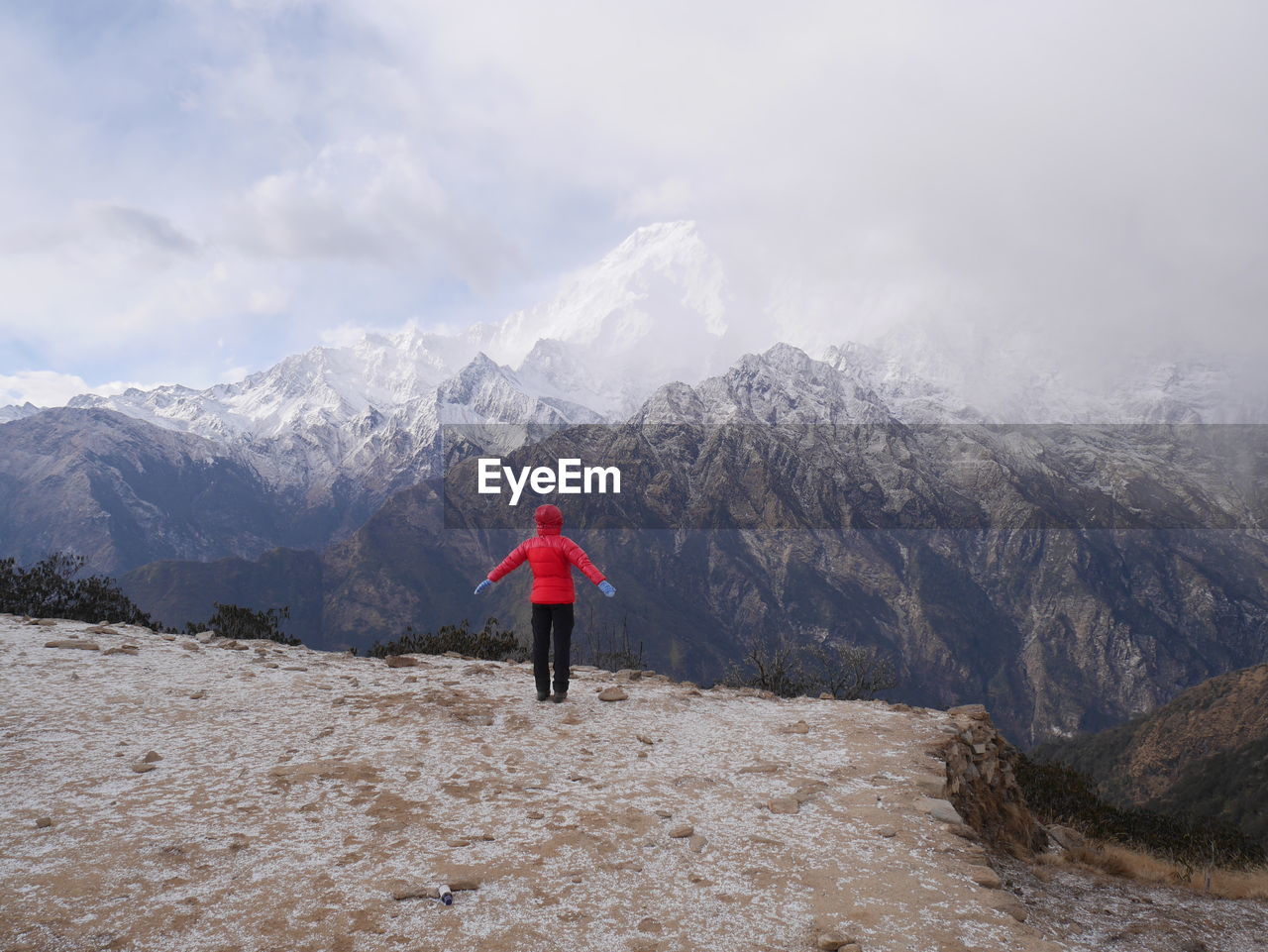 Rear view of person standing on snow covered land against mountains