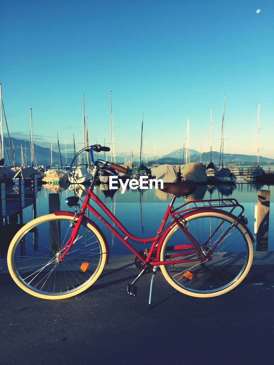 Bicycle on footpath by lake against sky