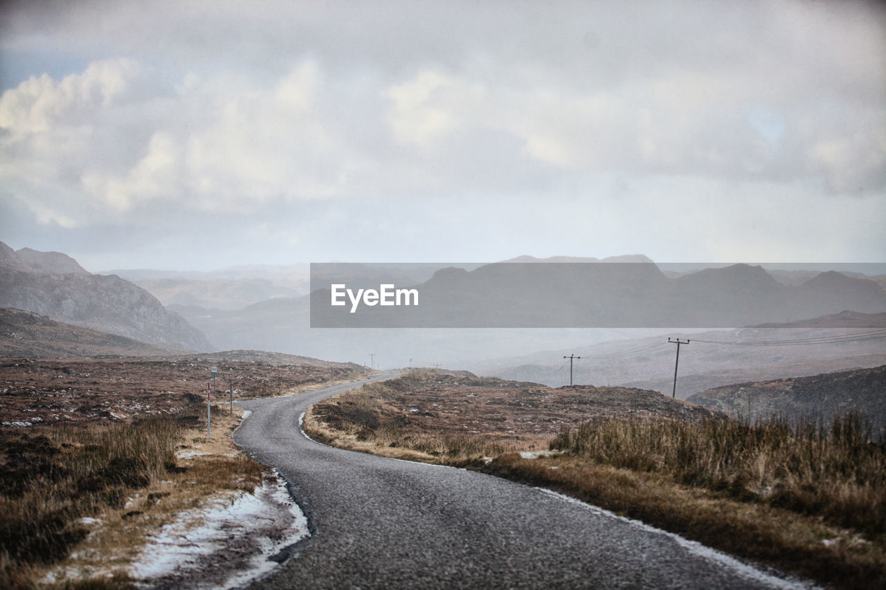 Road leading towards mountains against sky