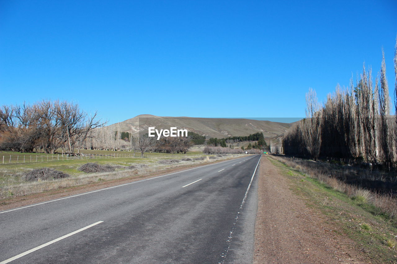 Country road against clear blue sky