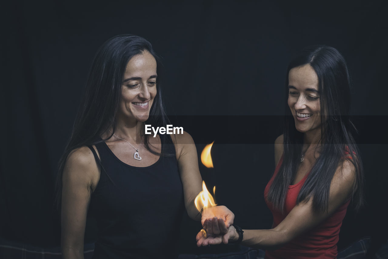 Two beautiful women holding a flame in their hands. 