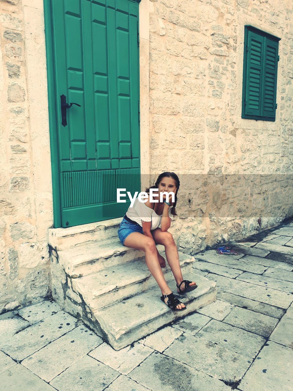 Portrait of woman sitting on steps outside house