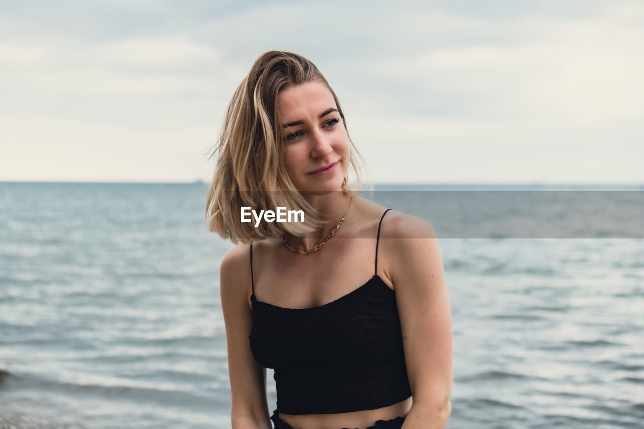 Young woman standing on blurred beachside background. attractive female enjoying walking the sea