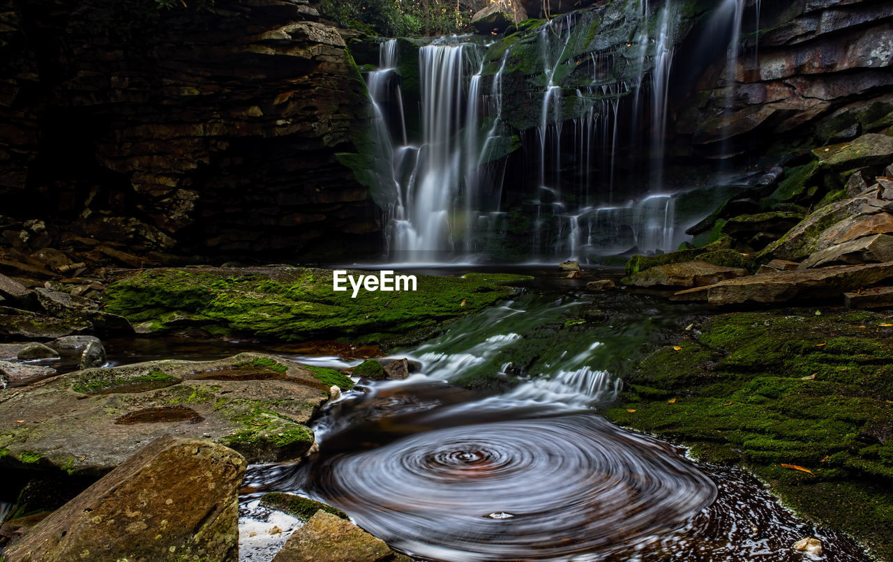 Waterfall and whirlpool on pond in forest