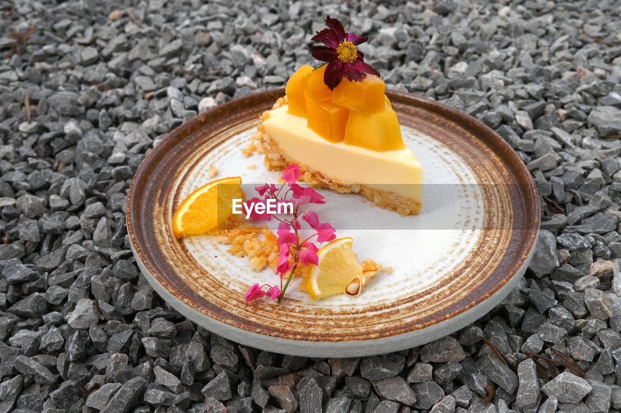 High angle view of mango cheesecake in a plate laid on the stone floor