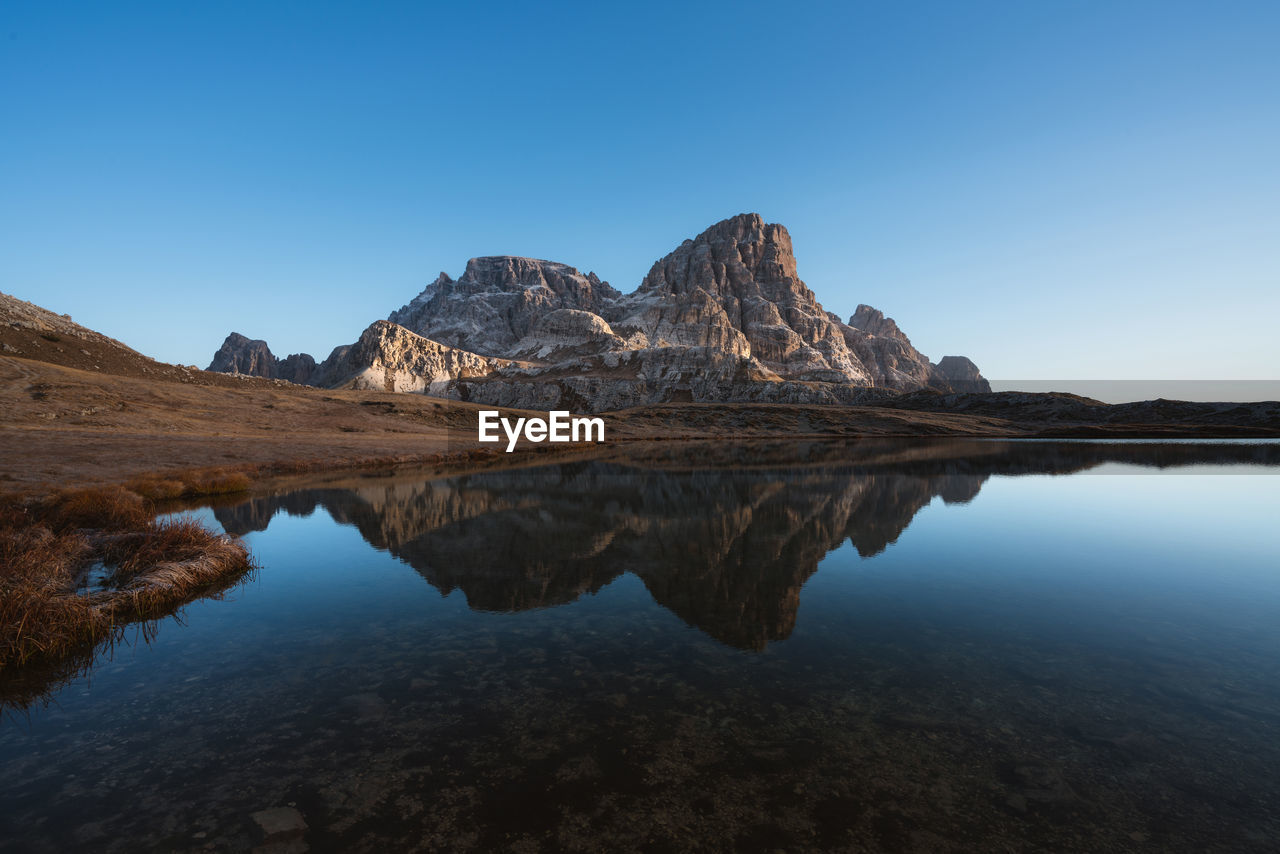 Scenic view of lake and mountains against clear blue sky