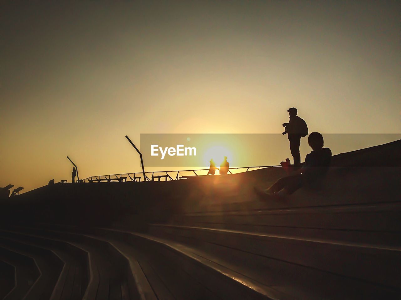 Low angle view of silhouette people on steps against orange sky