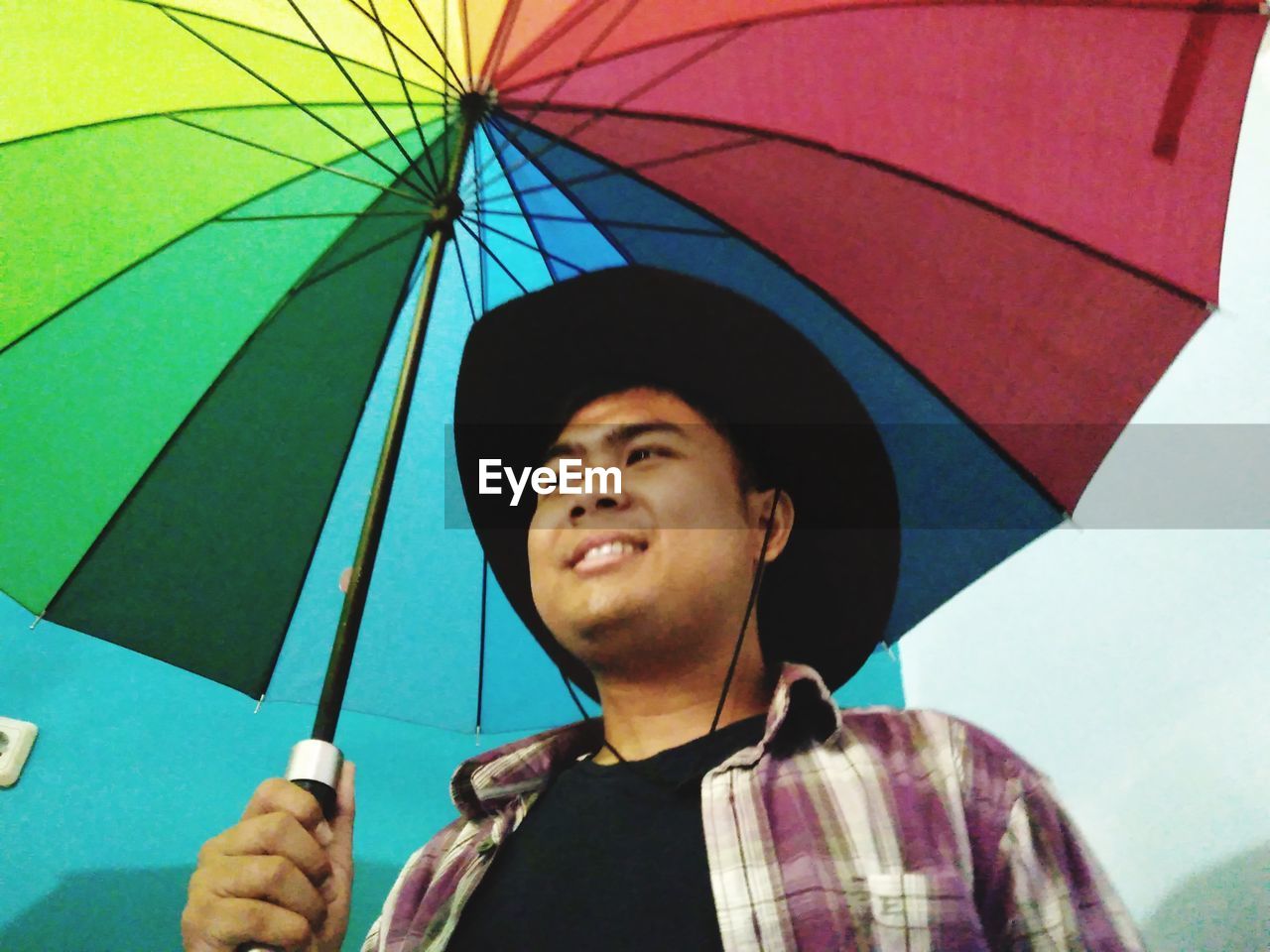 PORTRAIT OF A SMILING YOUNG MAN STANDING IN RAIN