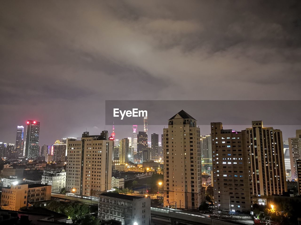 ILLUMINATED MODERN BUILDINGS IN CITY AGAINST SKY