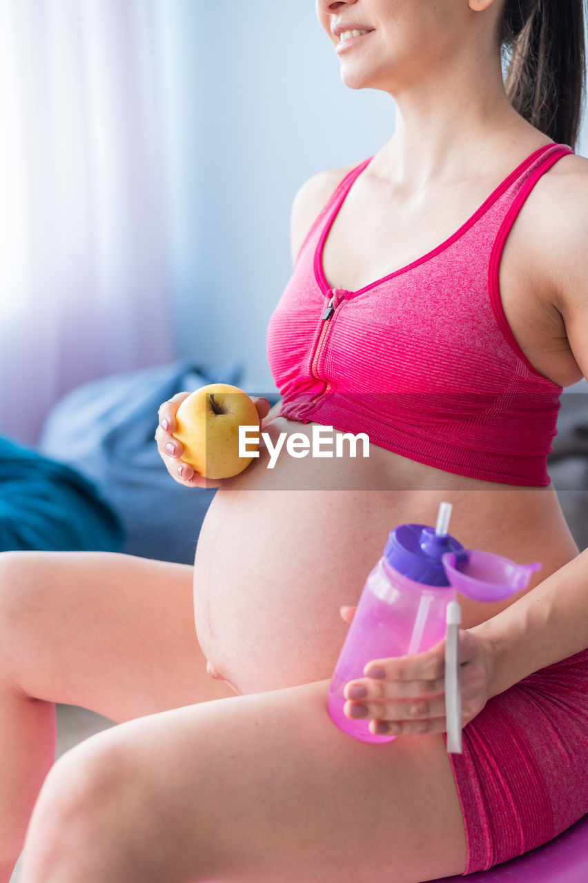 midsection of woman holding apple