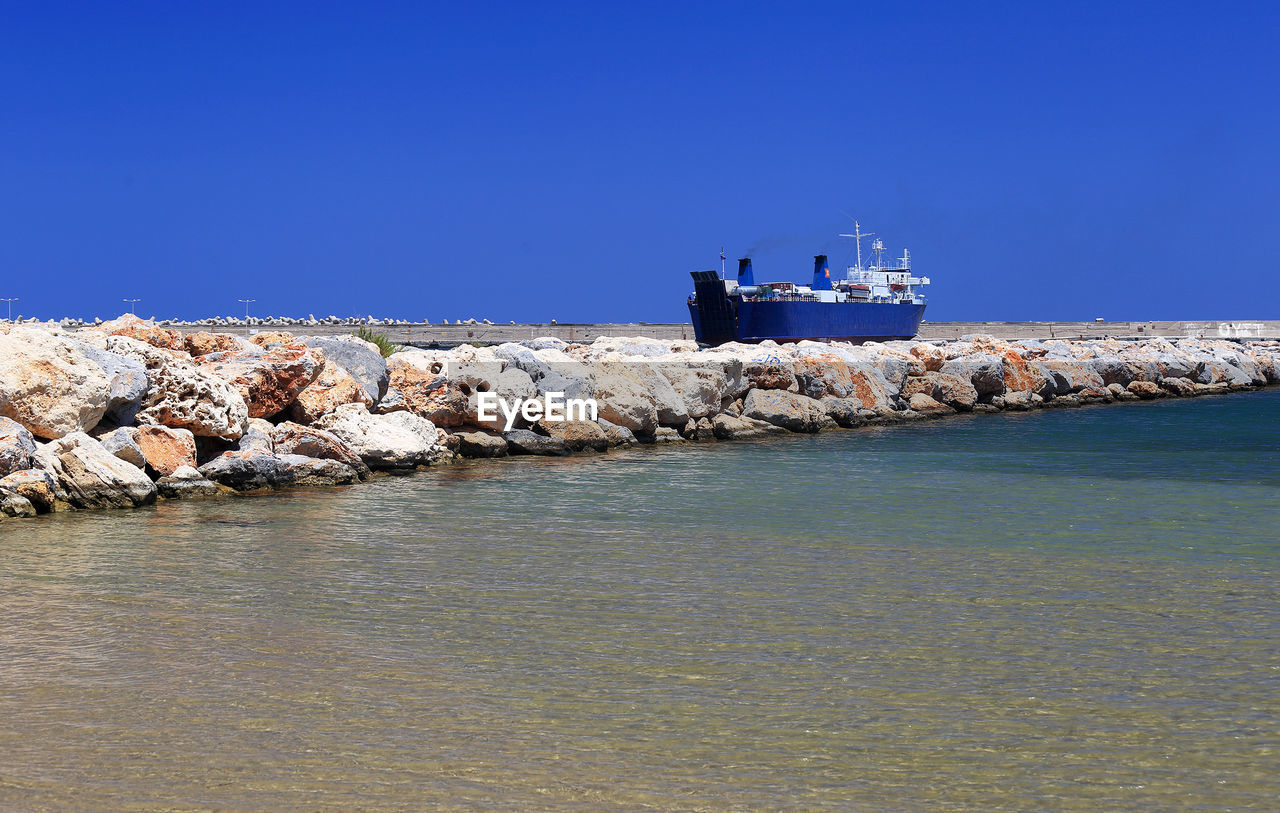 Boat moored at shore against blue sky