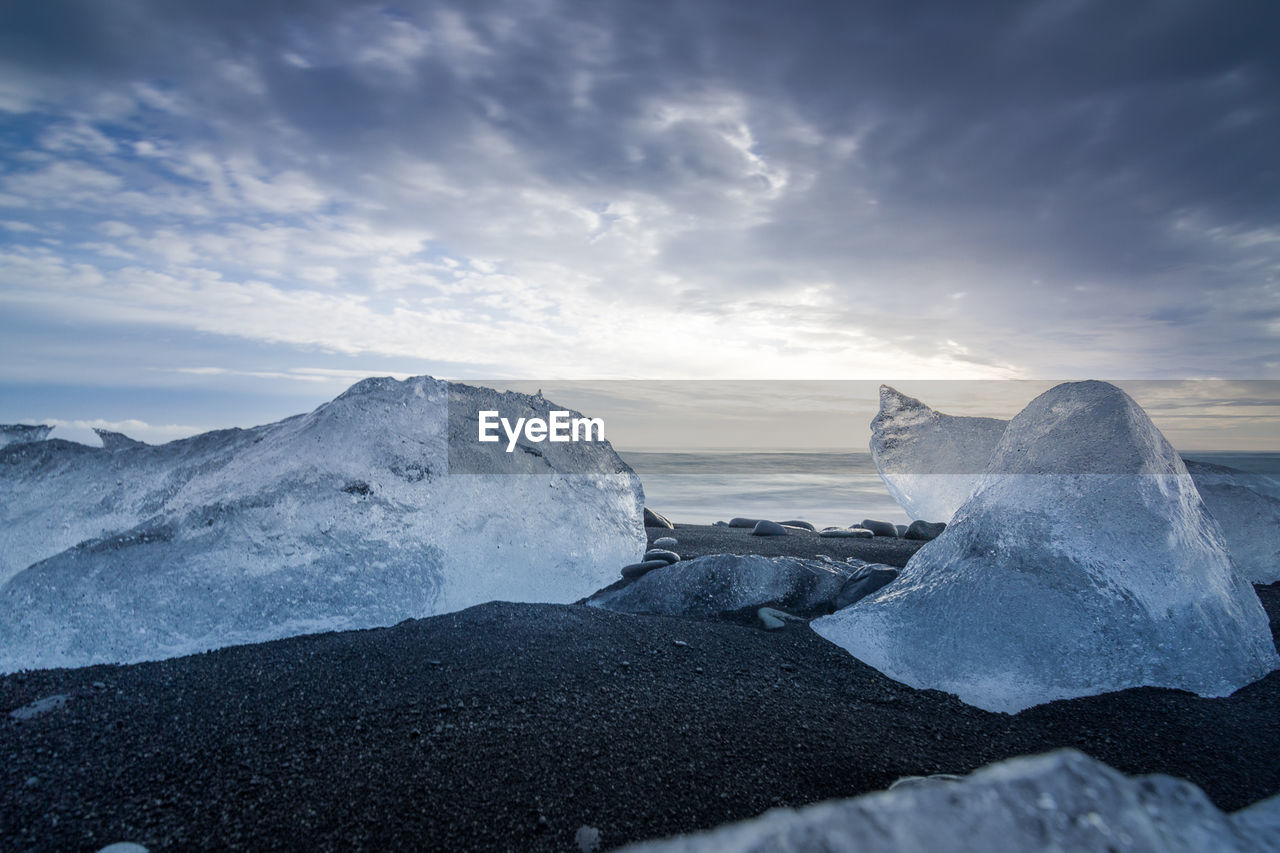 Ice at beach against sky during sunset