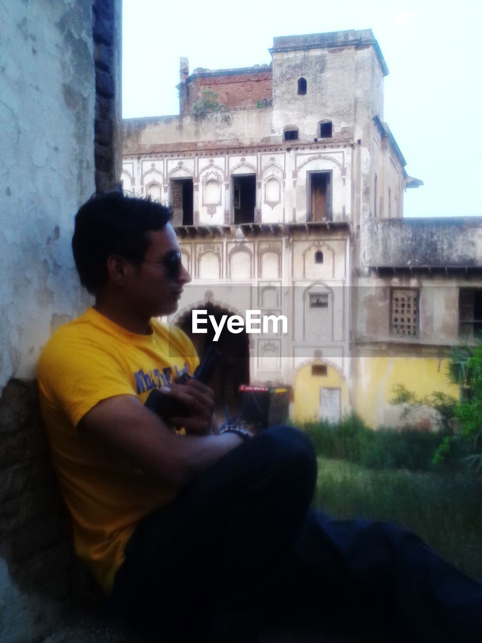 architecture, built structure, building exterior, sitting, one person, men, building, casual clothing, adult, young adult, day, lifestyles, leisure activity, nature, side view, city, outdoors, three quarter length, looking, window