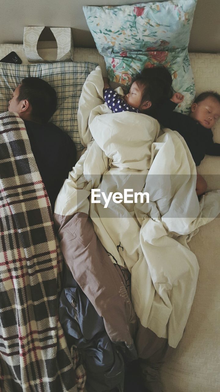 Family sleeping on bed at home