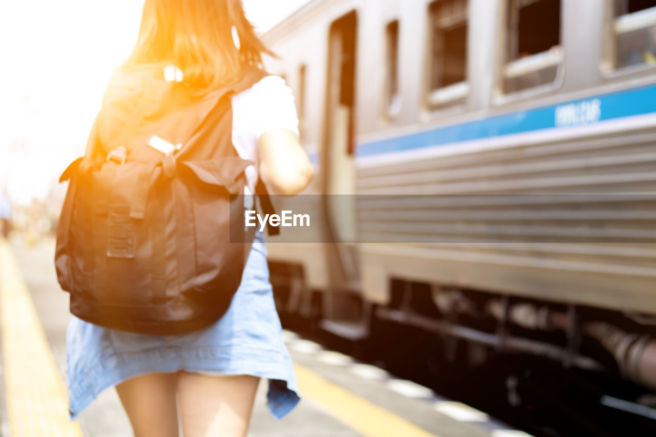 Rear view of woman carrying backpack while standing by train