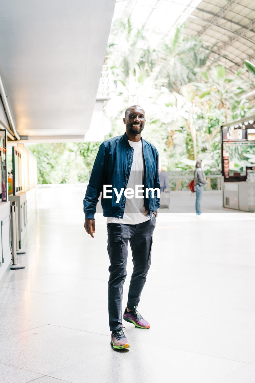 Afro american young stylish man standing in station with mobile phone