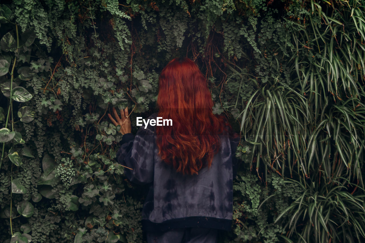 Redhead woman standing against plants